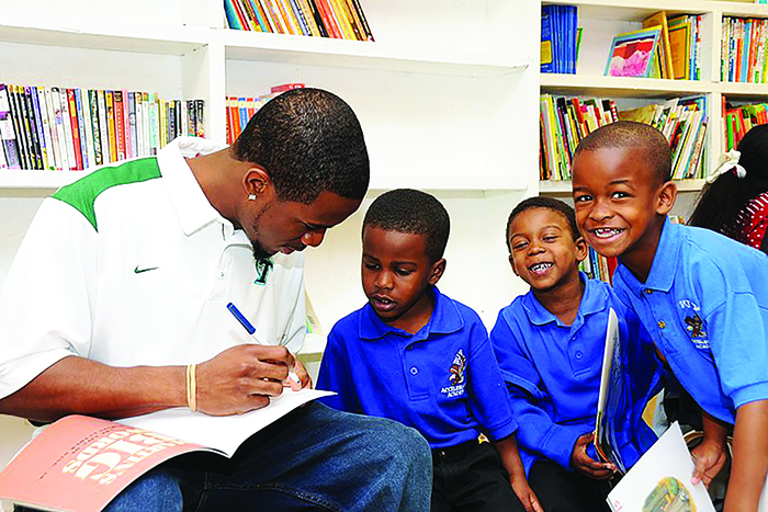 Male Teacher with book with three male students