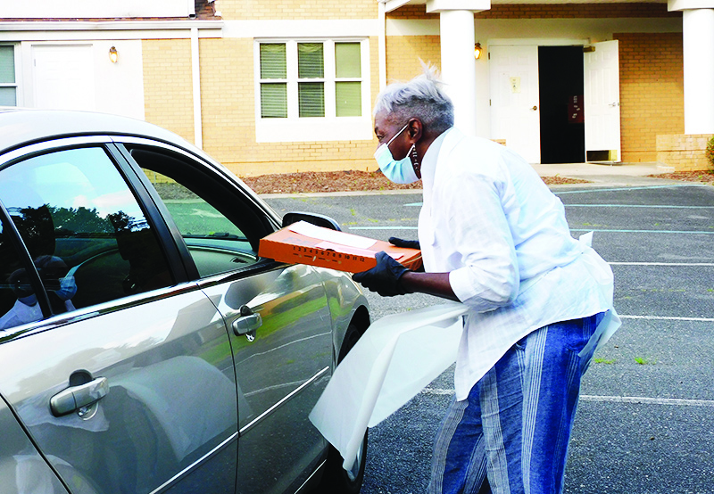 Simpson-Gillespie Members hands pizza to participant