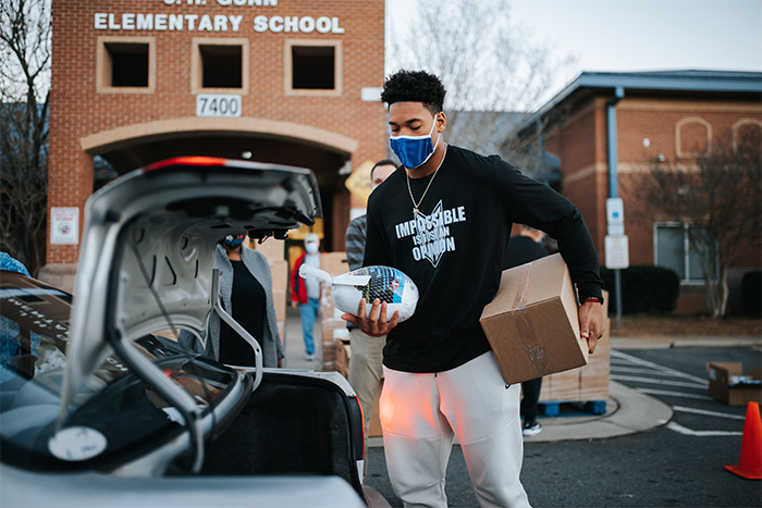 Yetur placing a turkey and condiments in a family's car